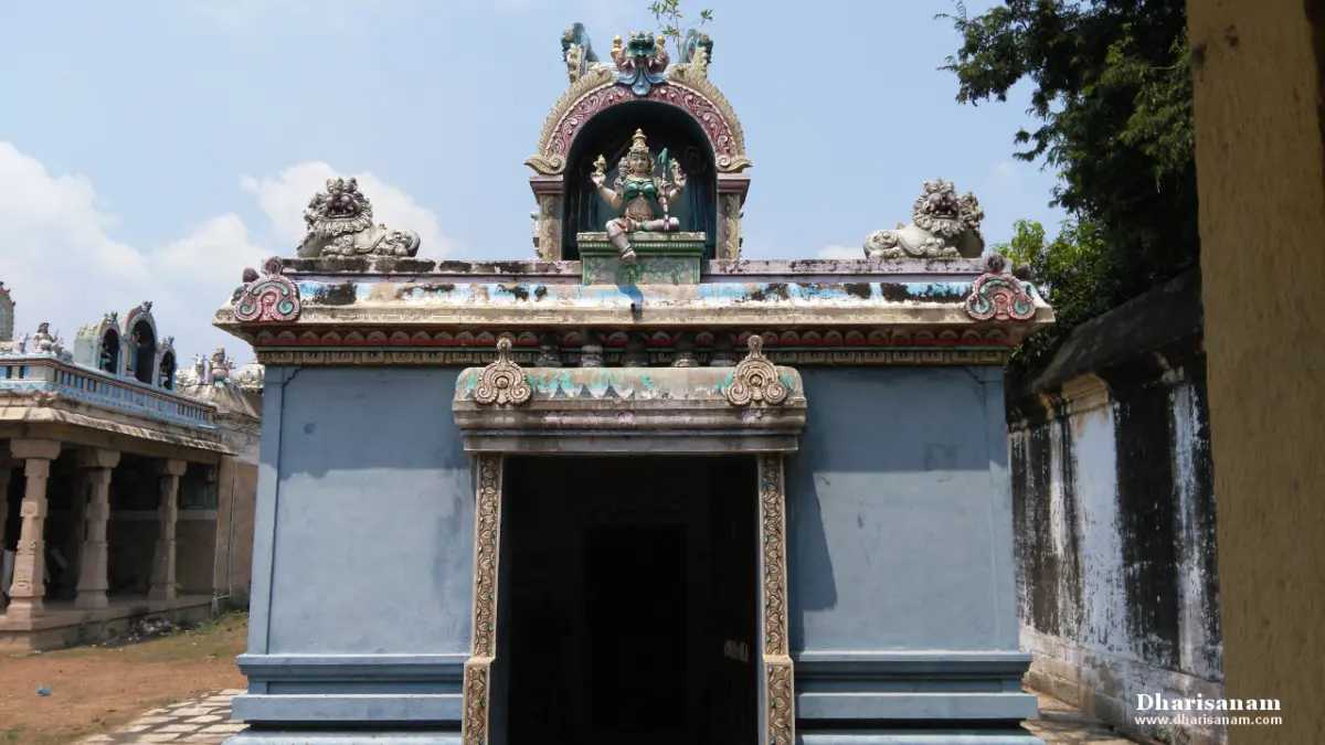 Blue-painted shrine doorway topped by a seated deity figure, with stone lions on the roof