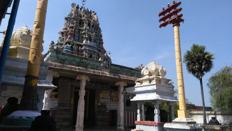 Sculpted tower over a pillared hall, with flag posts and a Nandi pavilion in front