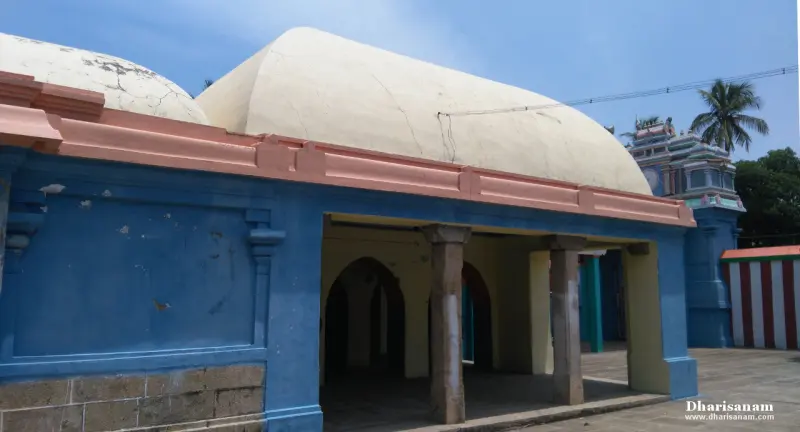 A hall with arched openings and a pale rounded roof, with a tower visible behind it.