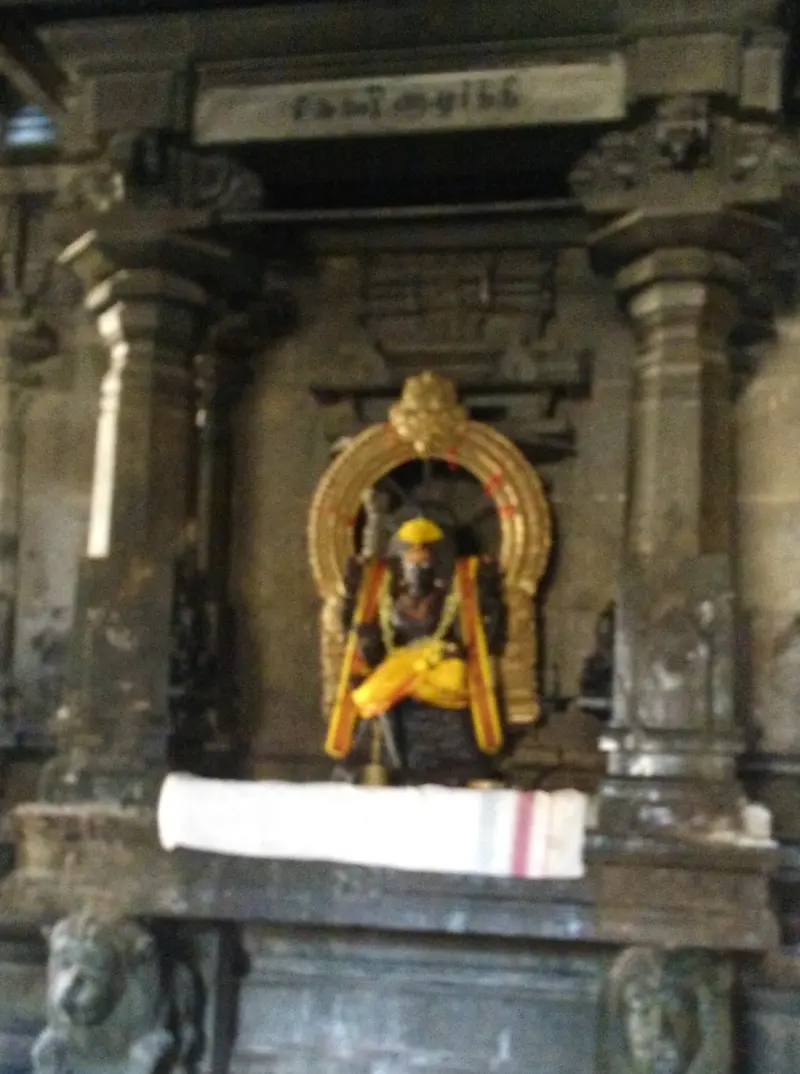 Standing four-armed idol in yellow garments under a gold arch