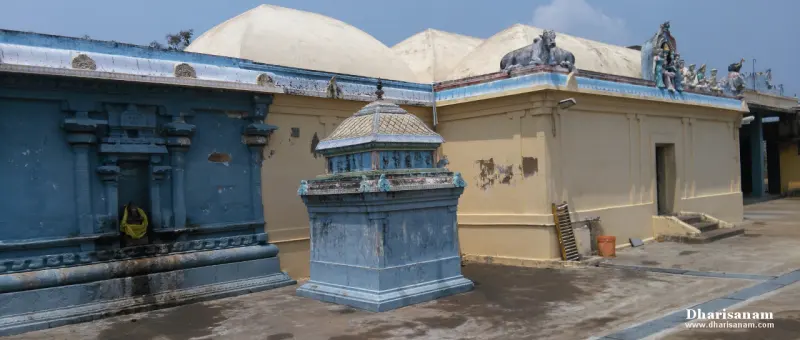A small domed blue shrine in the foreground, with a larger blue shrine and pale domes beyond