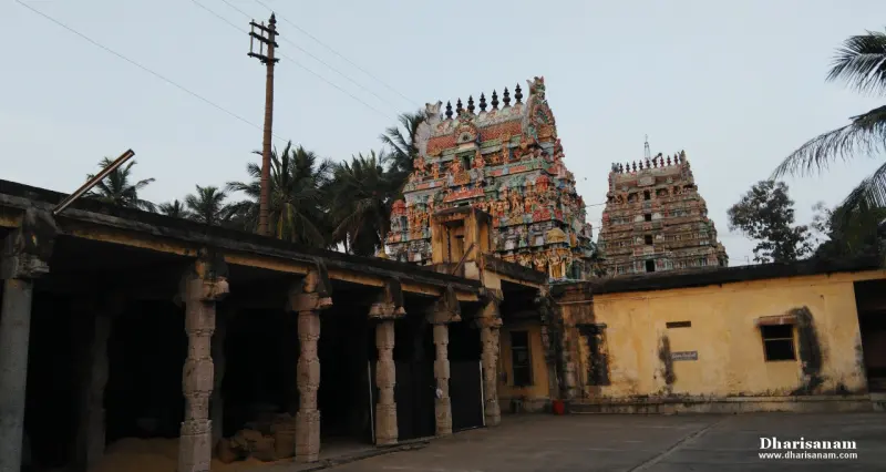Two towers over a yellow-walled courtyard with a pillared hall at left and coconut palms behind