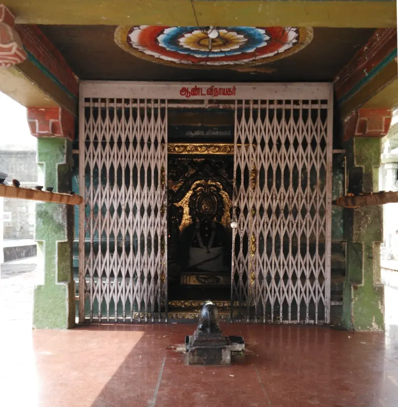 Gated shrine with a name board and dark idol inside
