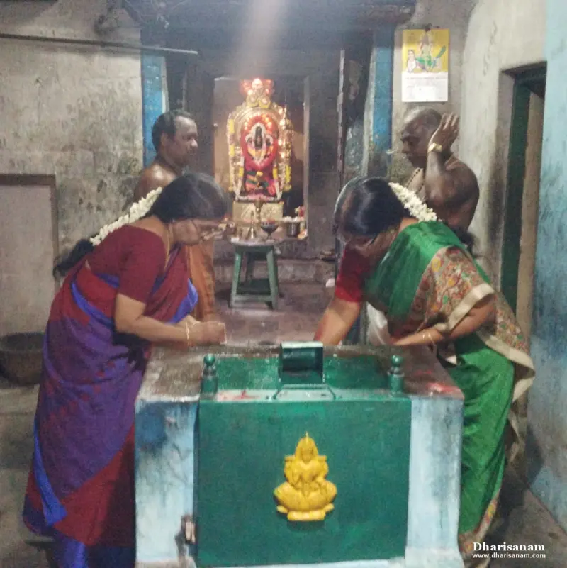 Two women and two men stand around a green altar facing a decorated shrine with a goddess figure inside
