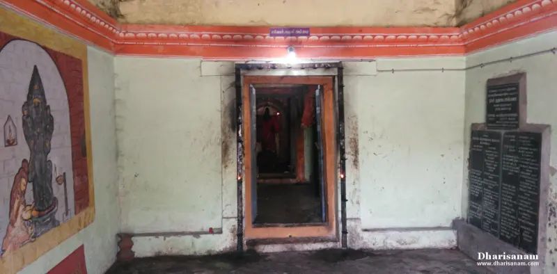 Hall with an orange-trimmed ceiling, a painted panel on the left, a central doorway and stone slabs on the right
