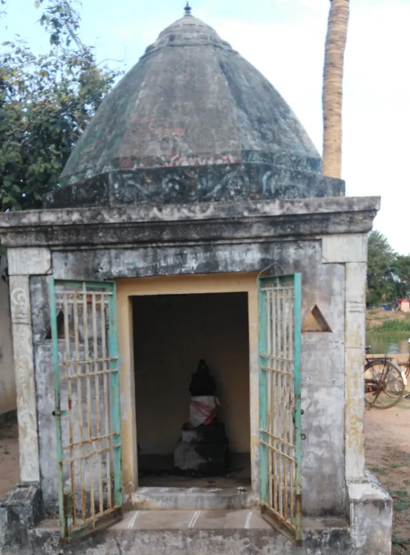 A small domed stone shrine with open grilled doors and a dark idol inside