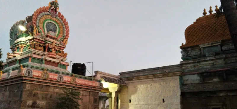 A colourful sculpted tower on the left and a plain stone tower on the right, above temple walls.