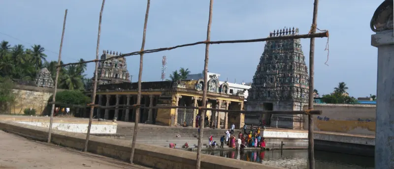Devotees on the steps of the tank, with a pillared hall and a tall tower behind