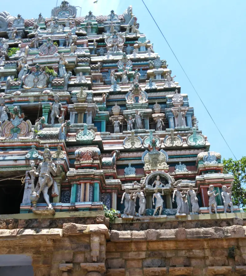 Close view of a tower's lower tiers with rows of small painted figures and a large standing figure at left.