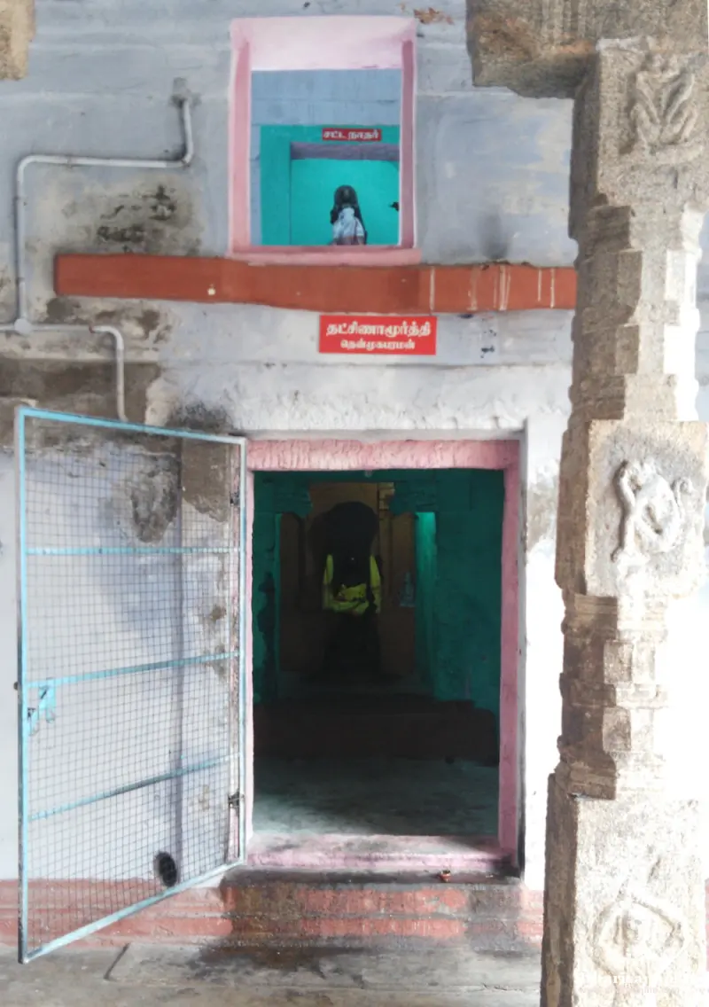 Doorway with a red Tamil name board and a small window shrine above, with an idol seen inside
