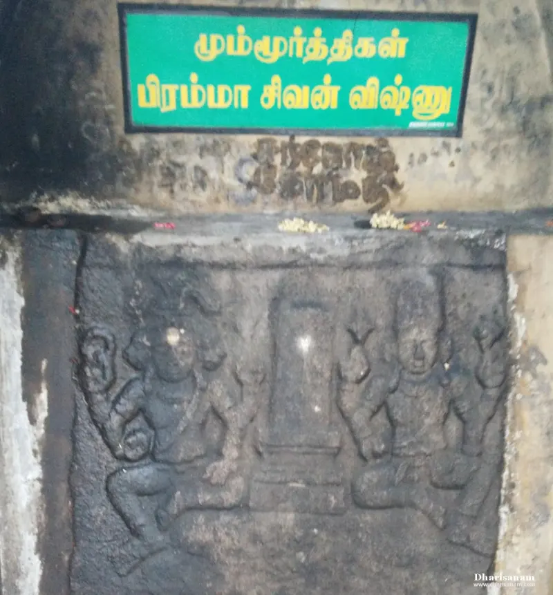 A stone relief of two seated figures with a lingam between them, a green sign above naming the three