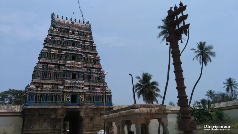 Colourful five-tier tower beside a tall dark flagstaff and palms
