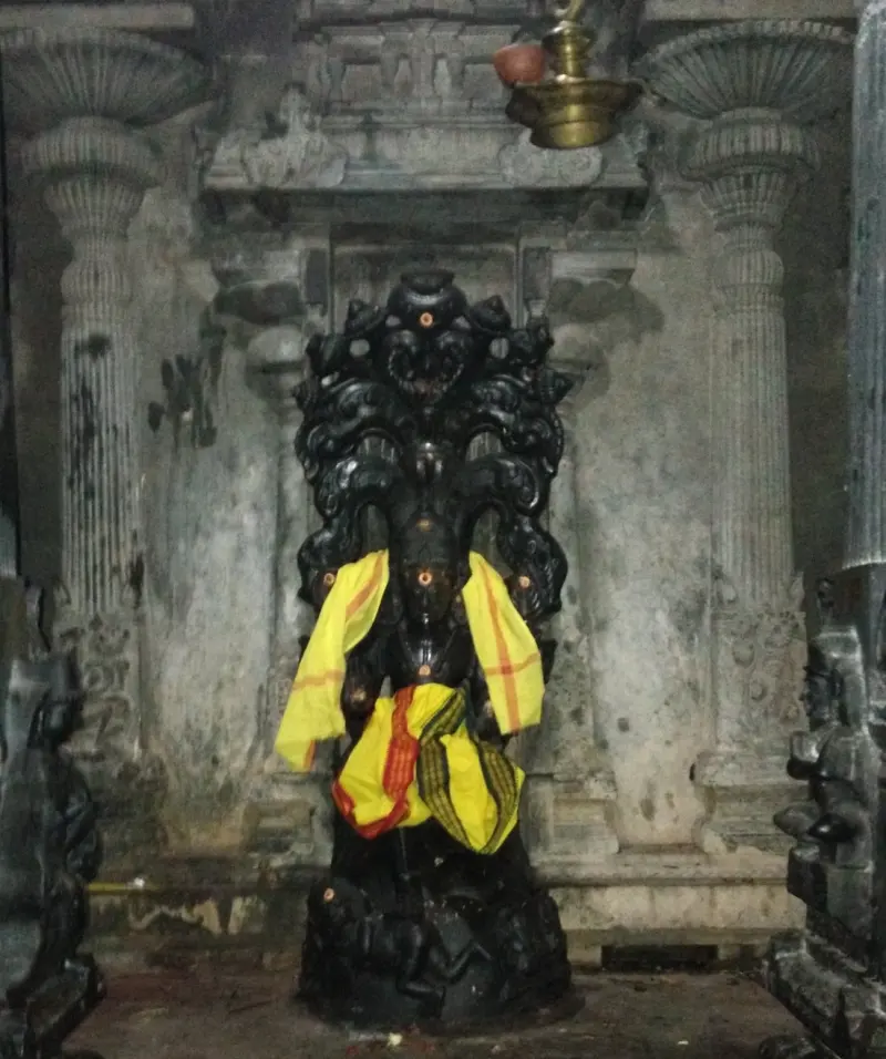 A dark stone idol in a niche, with a yellow cloth