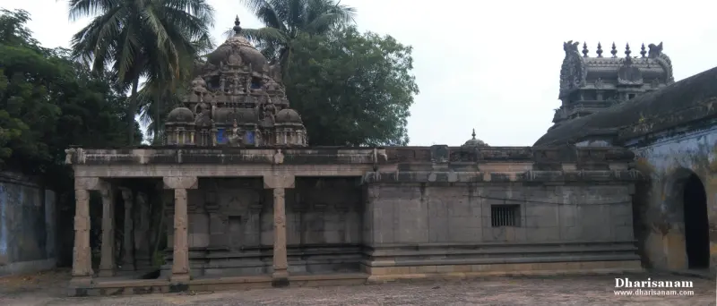 A stone hall with a pillared porch, a sculpted shrine tower behind it and the main tower at right