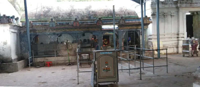 A shrine front behind iron railings, with a metal cabinet in front and the stone floor of the corridor.