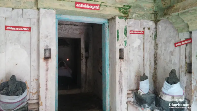 A doorway with red name boards for Kasi Viswanathar, Vinayakar, Murugan and Chandikeswarar; small idols on stone bases.