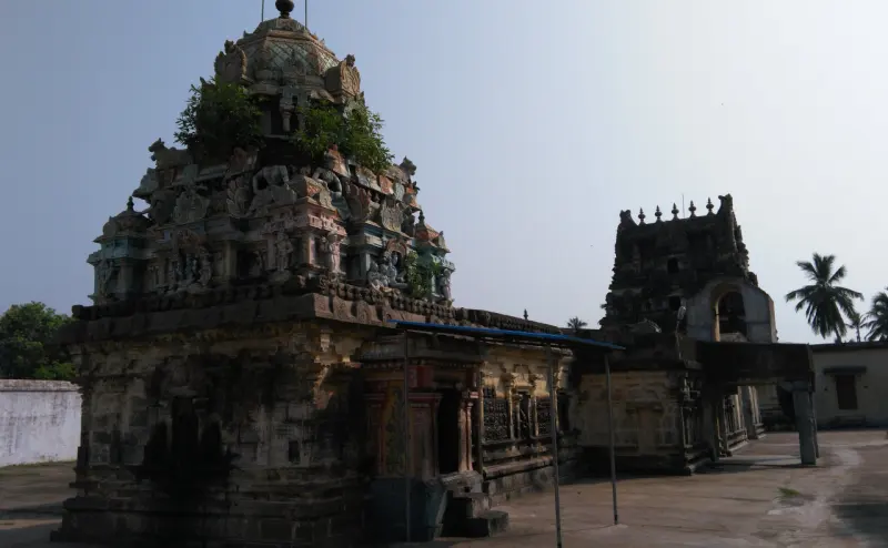 A weathered stone sanctum with a painted tower, and a dark entrance tower to its right in the dim light.