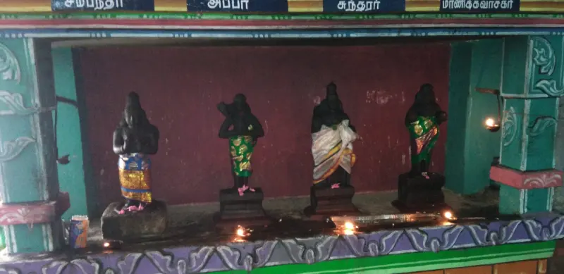 Four dark standing statues with lamps burning before them