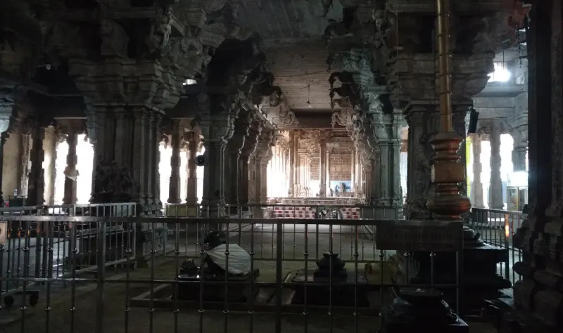 Rows of stone pillars in a dim hall, seen through a metal railing.