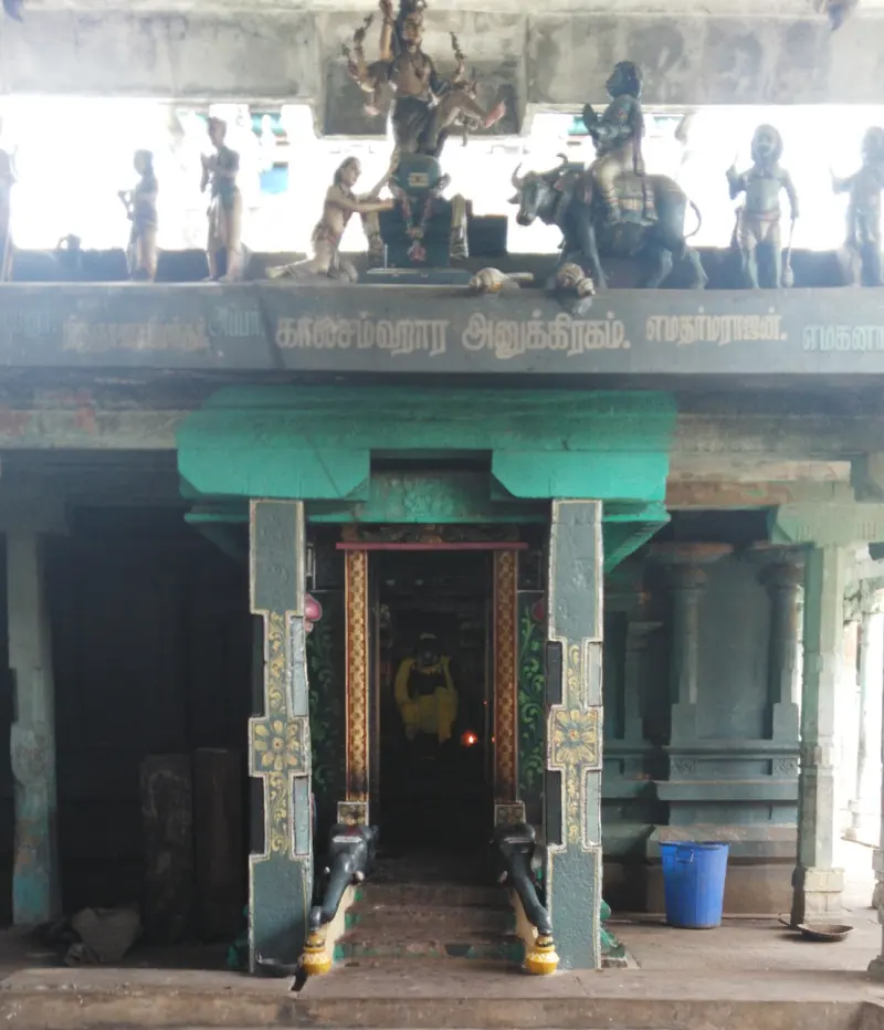 A shrine doorway with Tamil lettering on the lintel and painted figures above, one seated on a bull.