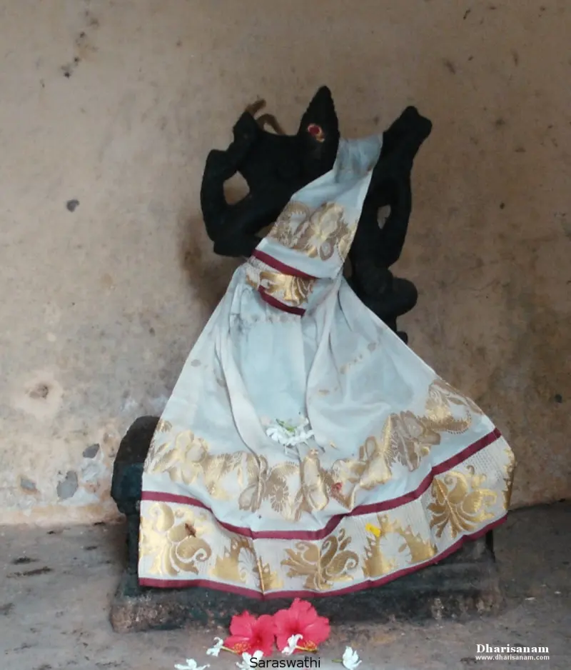 A black idol draped in a white and gold cloth