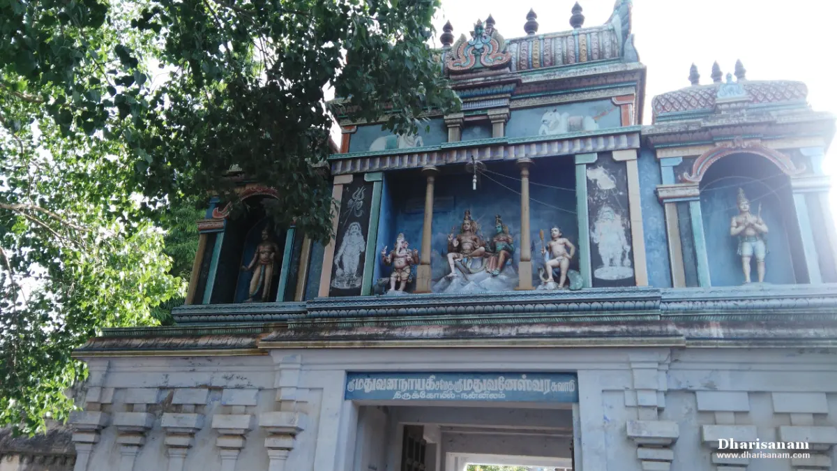 Painted figures in niches on a blue-walled gateway tower, with a name board over the entrance and a tree at left