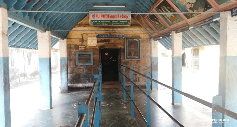 A covered walkway with railings leading to a dark doorway
