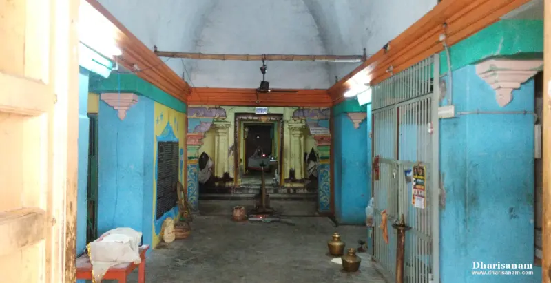 A blue-walled hall with brass pots on the floor and a lit sanctum doorway at the far end