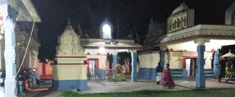 Small shrines with a pillared hall around an open courtyard, lit against the night sky