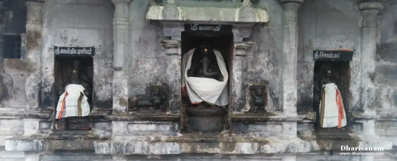 Three black stone idols in wall niches with name boards, the middle one Ganapathi draped in white cloth
