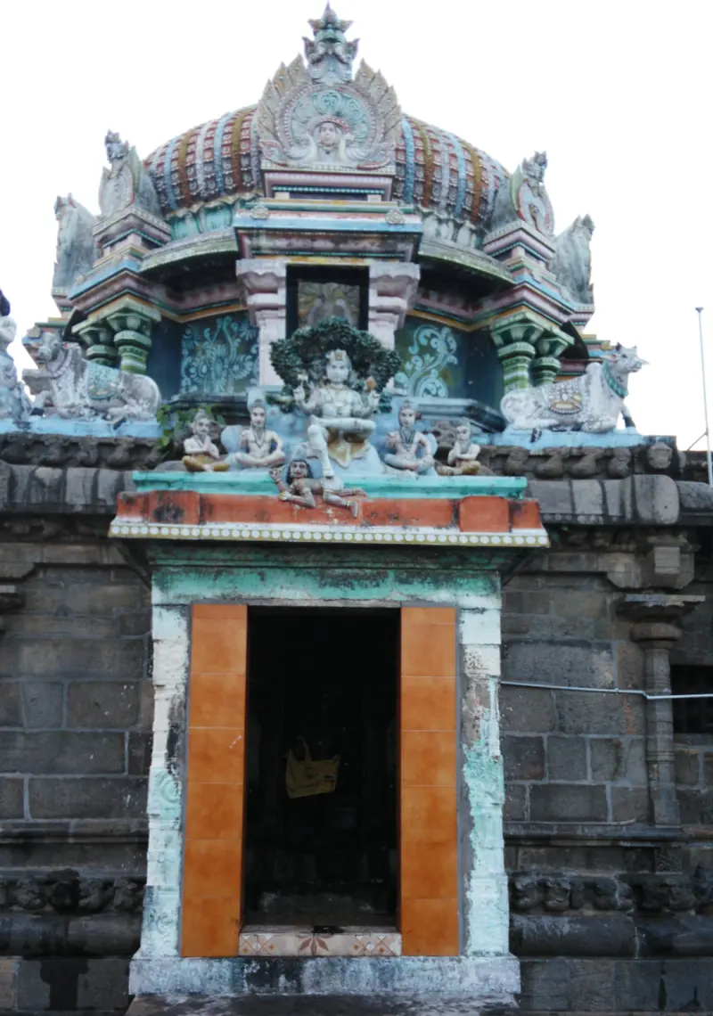 Small shrine with a colourful dome, seated figures and bulls above an orange doorway