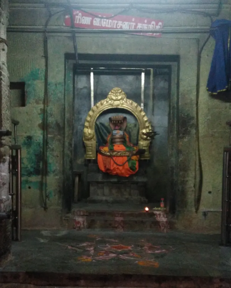 A dressed deity in a golden arch inside a shrine, with a name board above