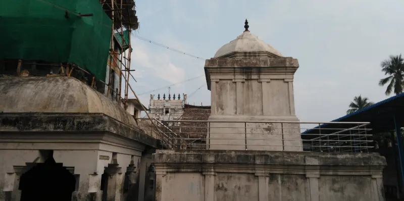 White shrine structures beside the corridor, with scaffolding covered in green netting at upper left.