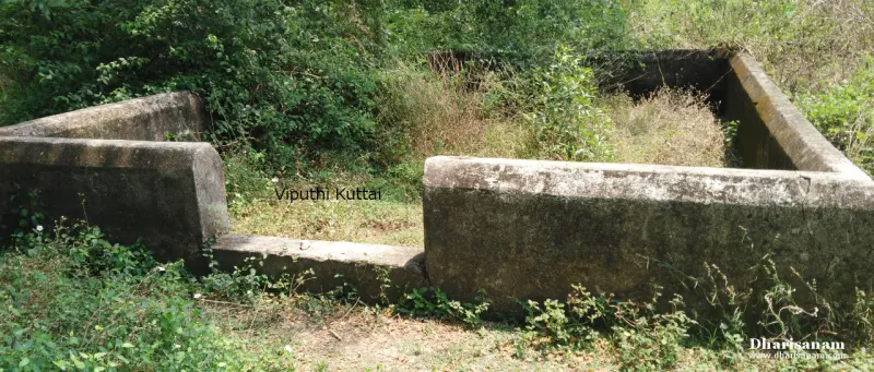 A low stone-walled enclosure overgrown with grass and shrubs, with the words Viputhi Kuttai written on the photo