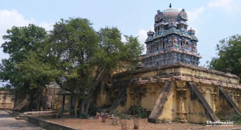 Colourful tiered tower rising behind yellow temple walls and trees
