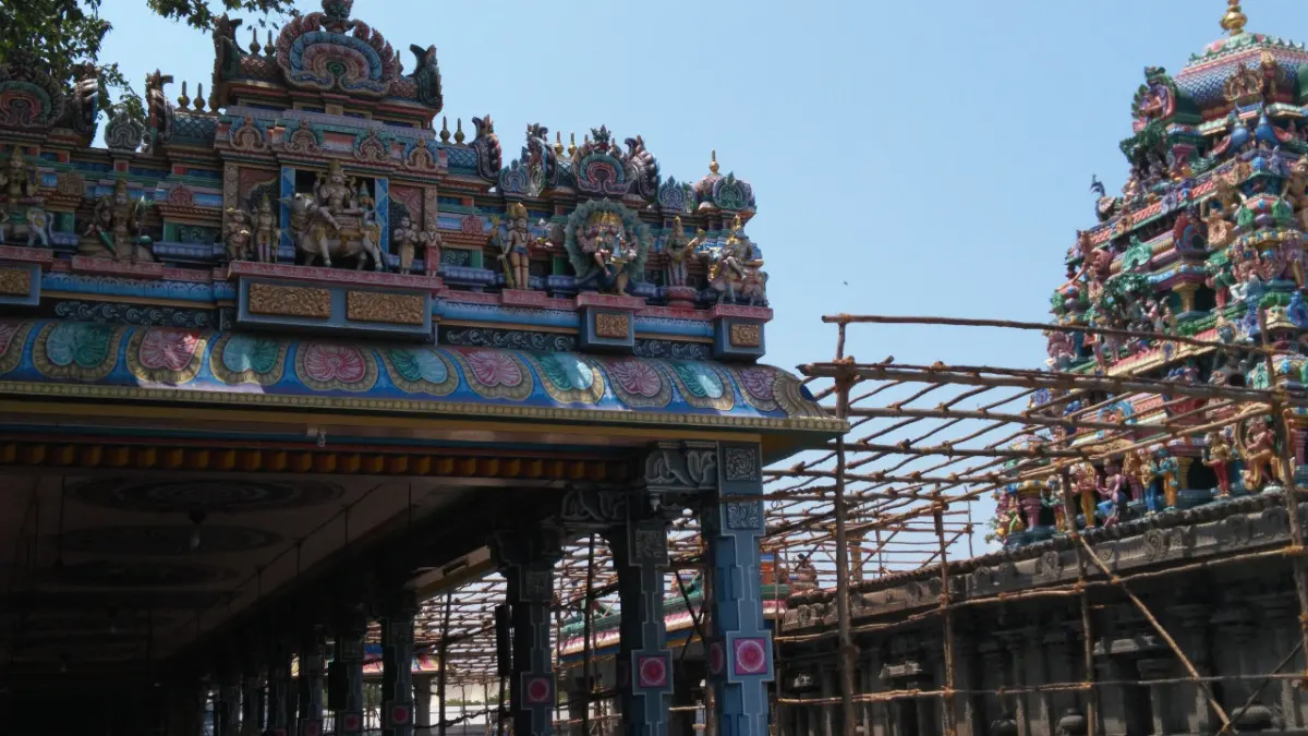 A painted tower above a porch on the left, and another tower rising behind bamboo scaffolding on the right.