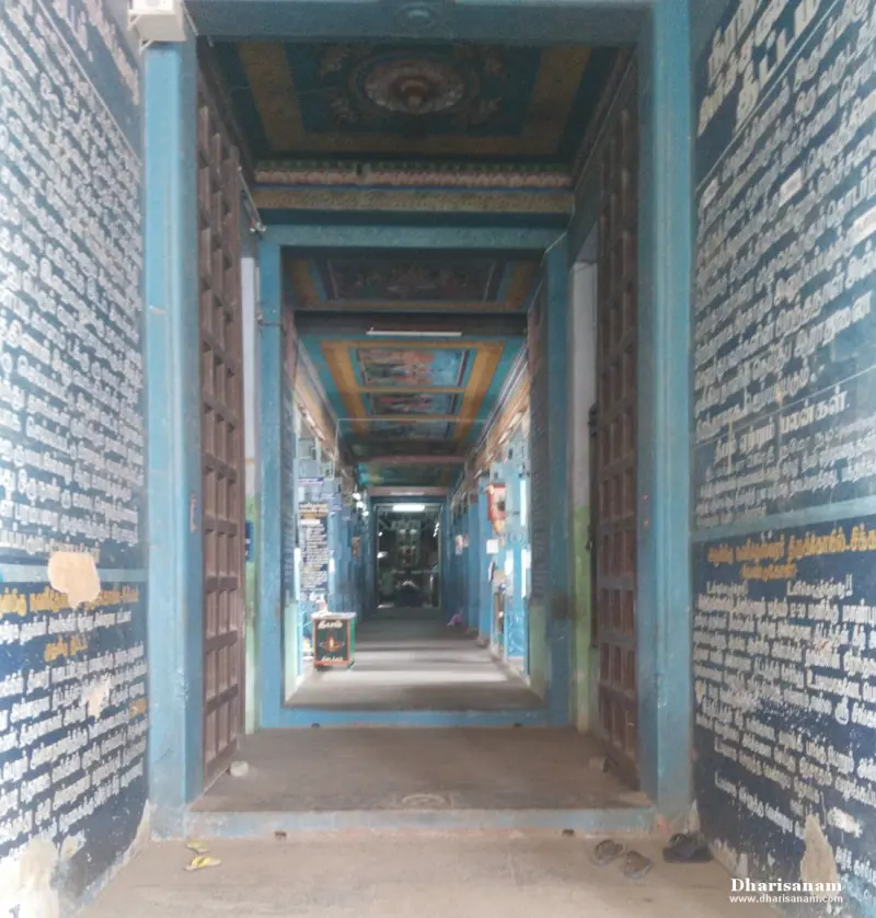 A long passage with doors, painted ceilings and walls filled with white Tamil writing on blue