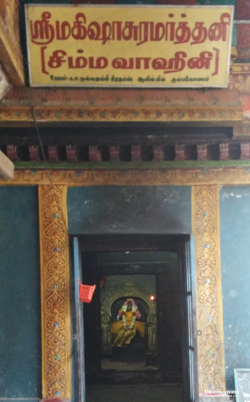 A shrine doorway under a yellow name board, with a garlanded goddess seated inside