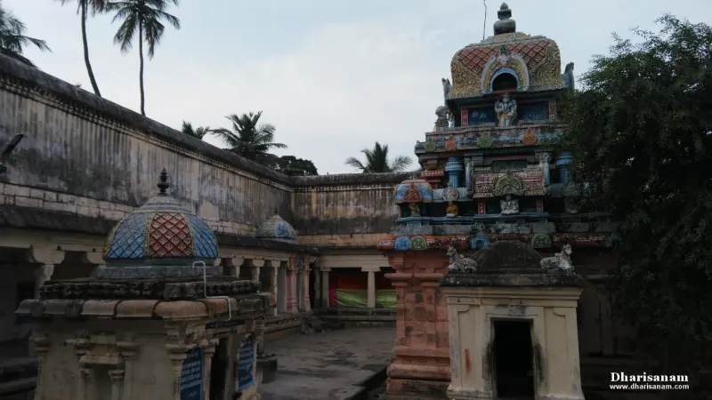 A coloured tower rising behind the corridor wall, with small domed shrines in the foreground