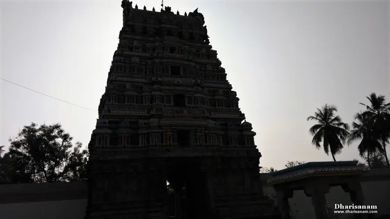 Dark silhouette of a tall tiered gopuram with palm trees at right