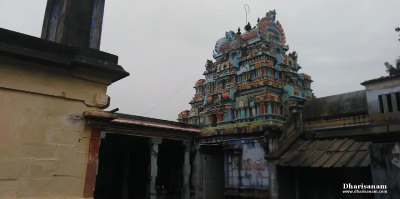 Multi-tiered painted tower in blue, red and green rising above old tiled and stone corridor roofs