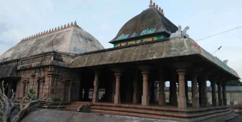 Side view of a pillared hall with curved roofs, with a larger domed roof rising behind it.