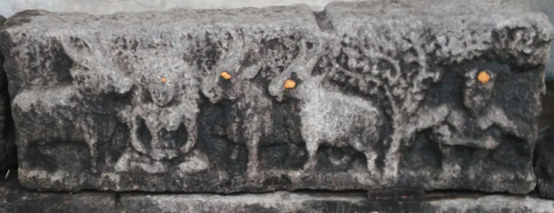 Weathered panel carved with cows and figures in a row