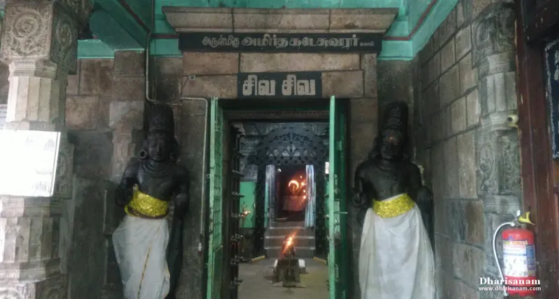 A doorway with two dark guardian figures in white and gold cloth, and a lamp lit inside.