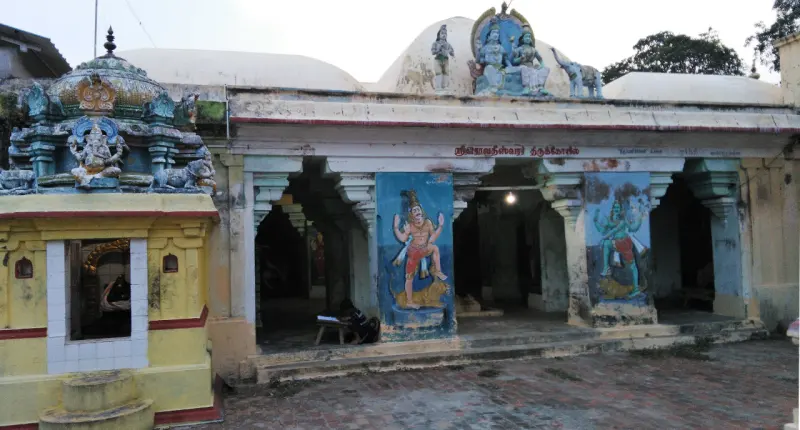 An open pillared hall with two painted figures on blue panels and a small shrine at the left.