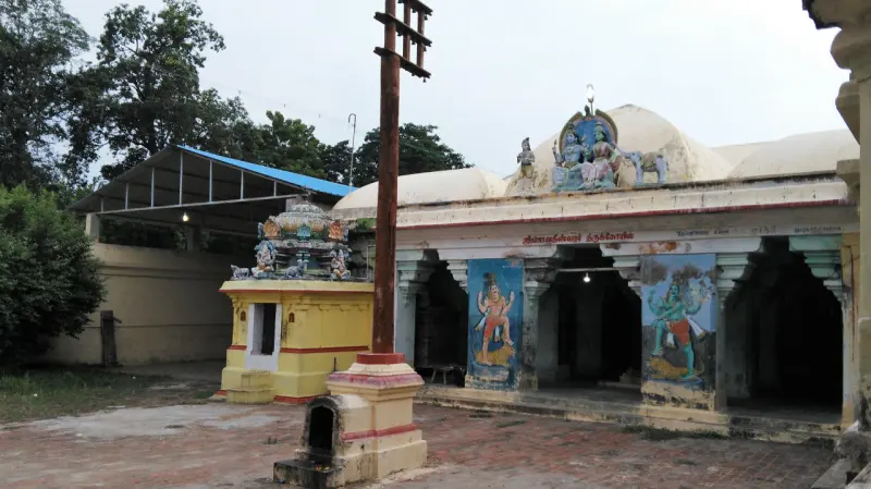 A flagstaff stands between a small yellow shrine and a pillared hall with painted figures.