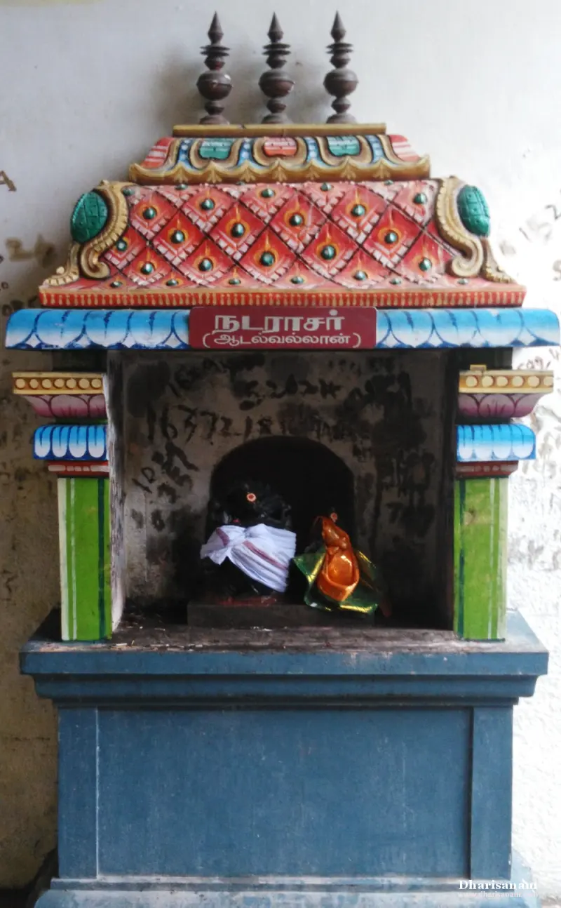 Small painted shrine with a Tamil name board, holding dark idols in cloth