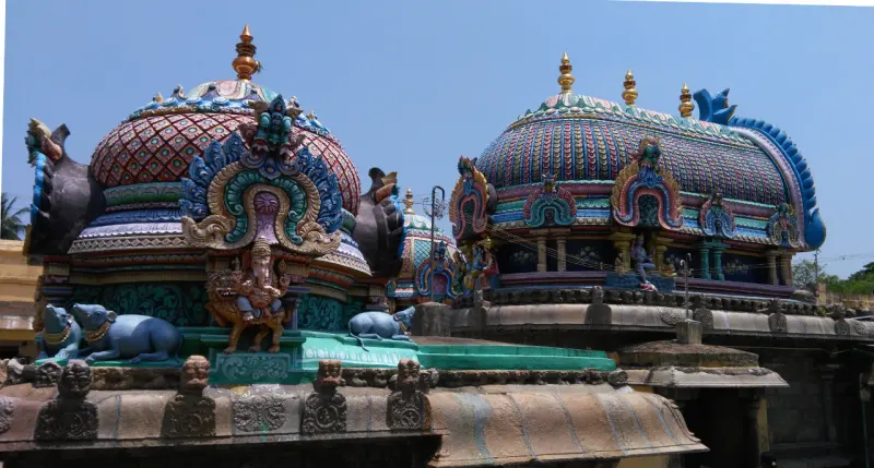 Two painted domes; the nearer shows a seated Vinayakar and blue bull statues on its base