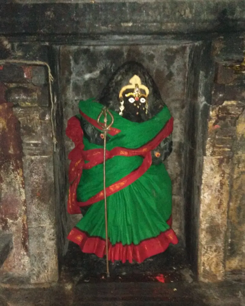 Black goddess in a green and red sari holding a trident