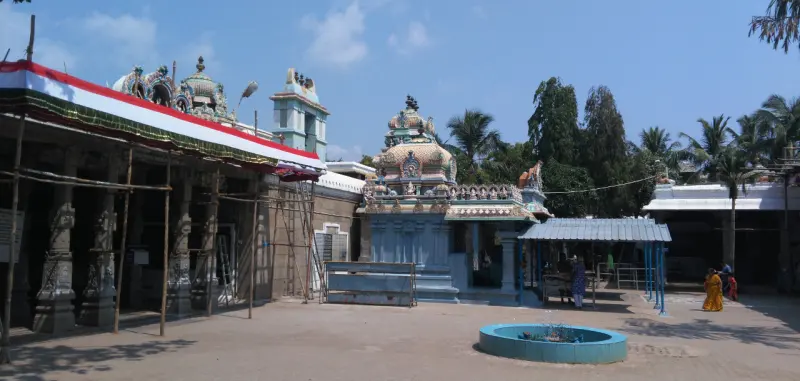 Small shrines with domed roofs in a sunlit courtyard, with a round blue basin in the foreground.
